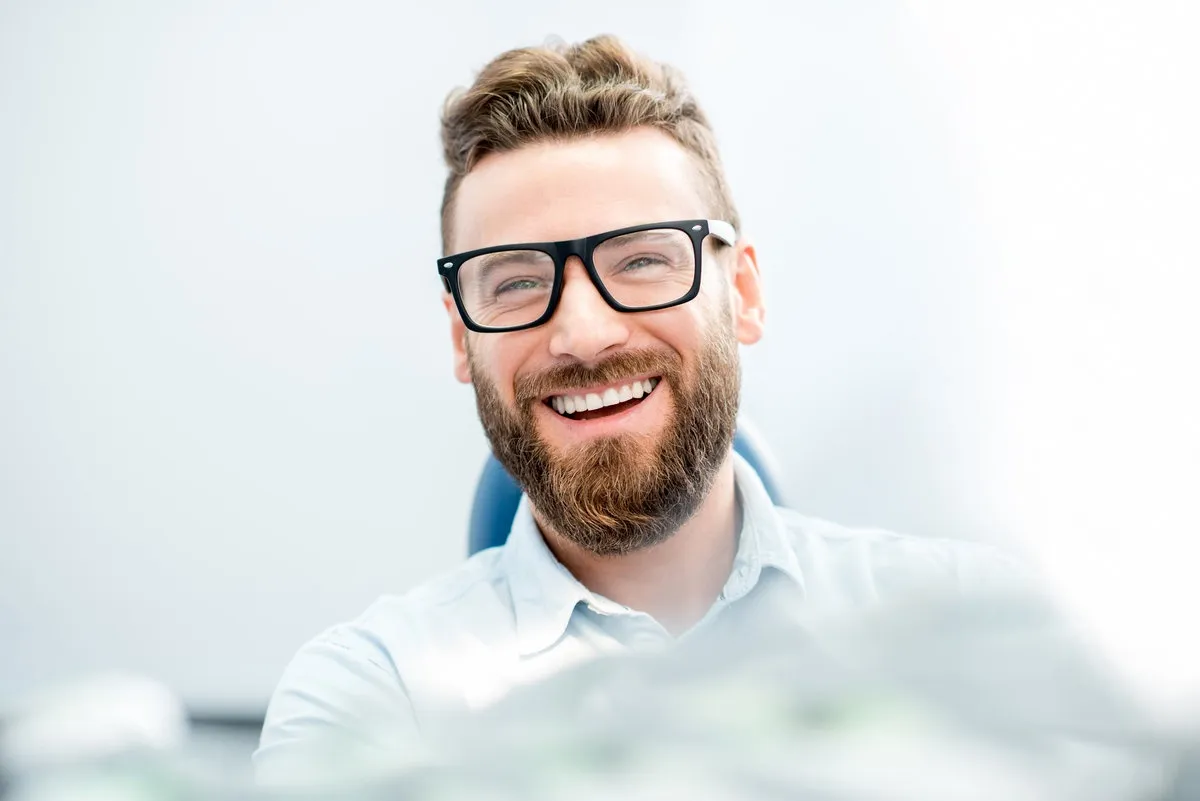 Couple smiling while looking at phone - Sunrise Dental Arts Care Handsome businessman with great smile sitting on the dental chair