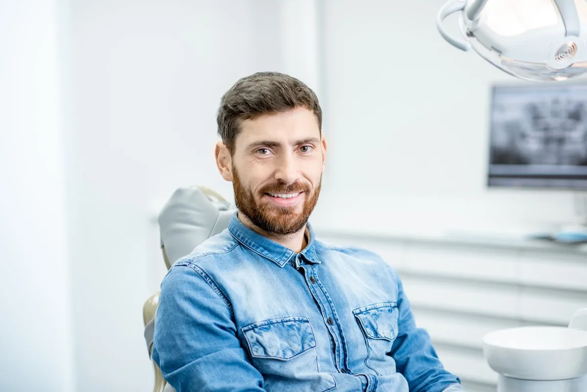Man pointing at bright smile - Sunrise Dental Arts Care Portrait of a handsome bearded man with healthy smile in the dental office