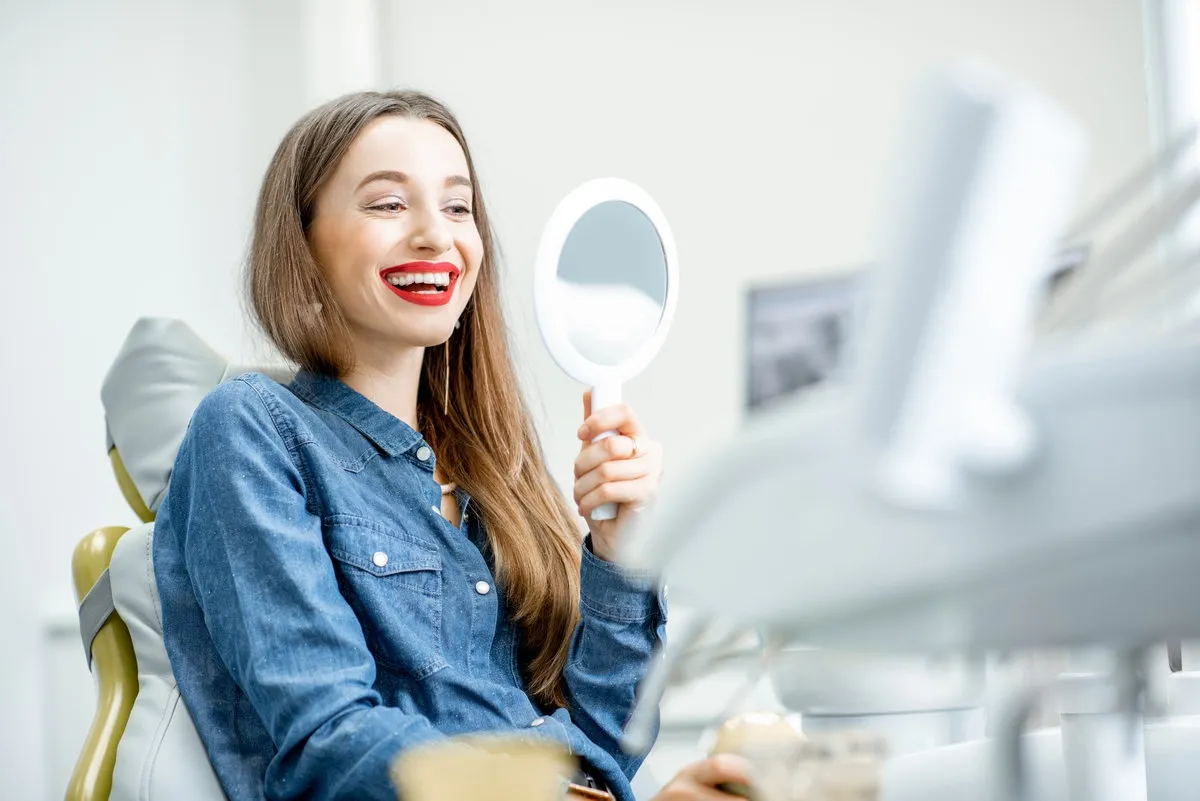 Happy couple smiling outdoors - Sunrise Dental Arts Care Portrait of a young beautiful woman looking on the mirror enjoying her beautiful smile in the dental office