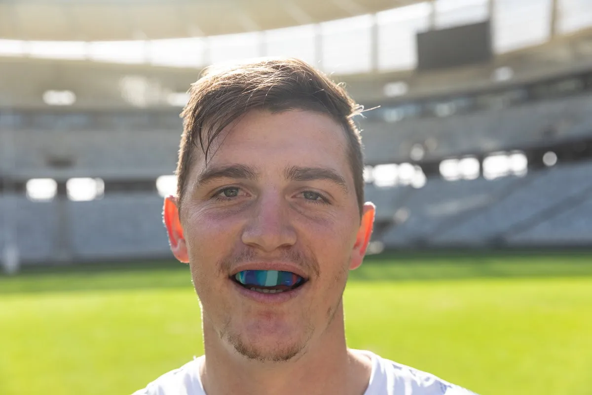 Man pointing at bright smile - Sunrise Dental Arts Care Male rugby player with mouth guard in stadium