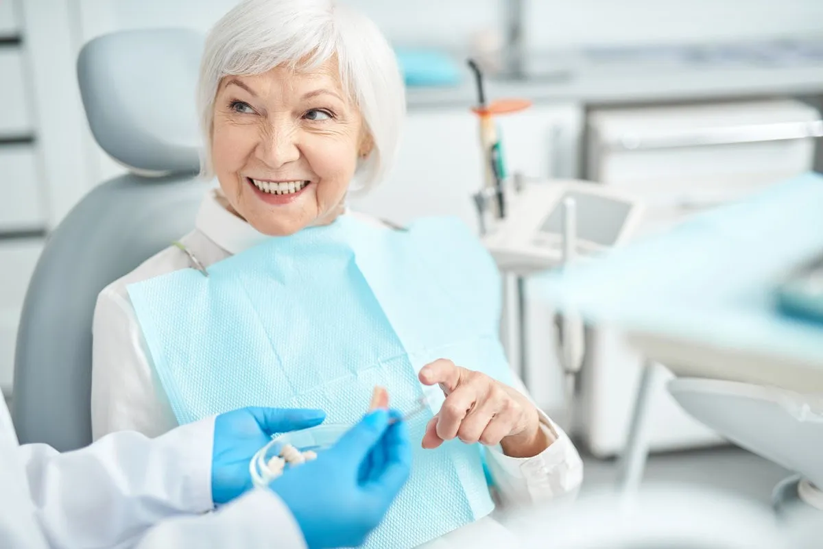 Happy couple smiling outdoors - Sunrise Dental Arts Care Dentist showing an old woman a denture