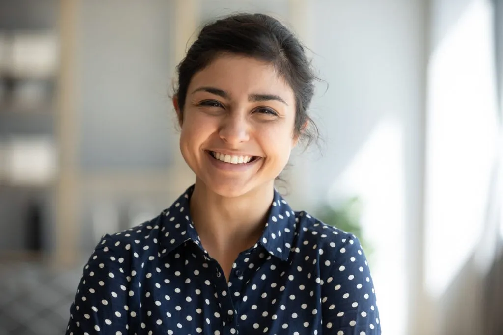 Couple smiling while looking at phone - Sunrise Dental Arts Care Cheerful beautiful indian girl student professional standing at home in office looking at camera, happy confident entrepreneur hindu lady laughing face posing alone, head shot close up view portrait