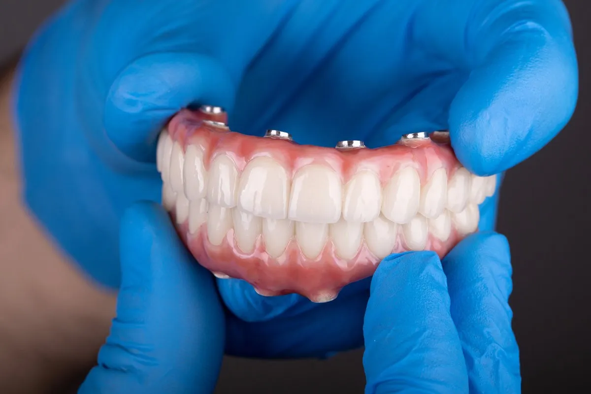 Couple smiling while looking at phone - Sunrise Dental Arts Care Dental prosthesis held by gloved hands