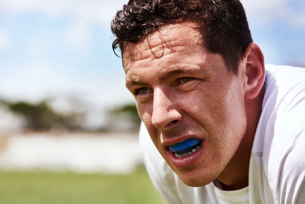Couple smiling while looking at phone - Sunrise Dental Arts Care Athlete wearing mouthguard, focused expression.