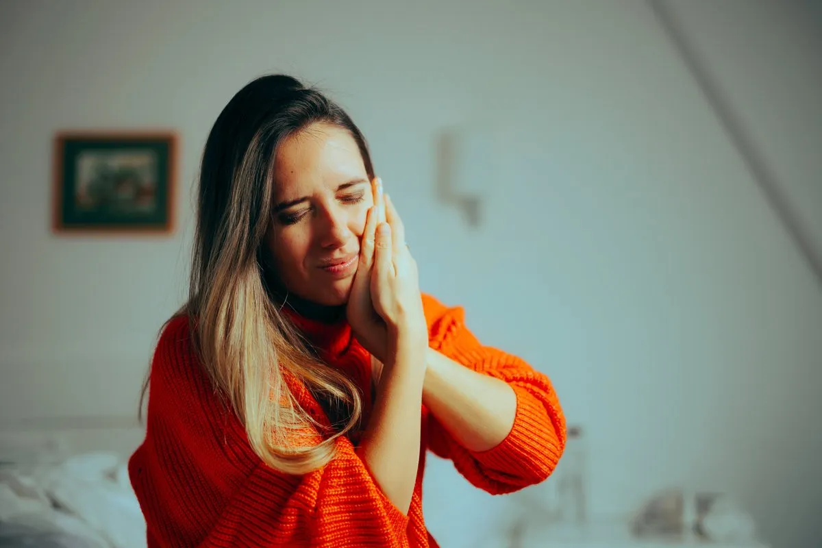 Couple smiling while looking at phone - Sunrise Dental Arts Care Woman holding her jaw in pain