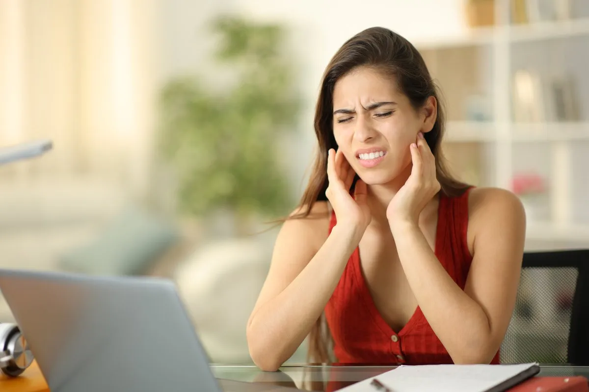 Man pointing at bright smile - Sunrise Dental Arts Care Beautiful woman suffering from jaw pain