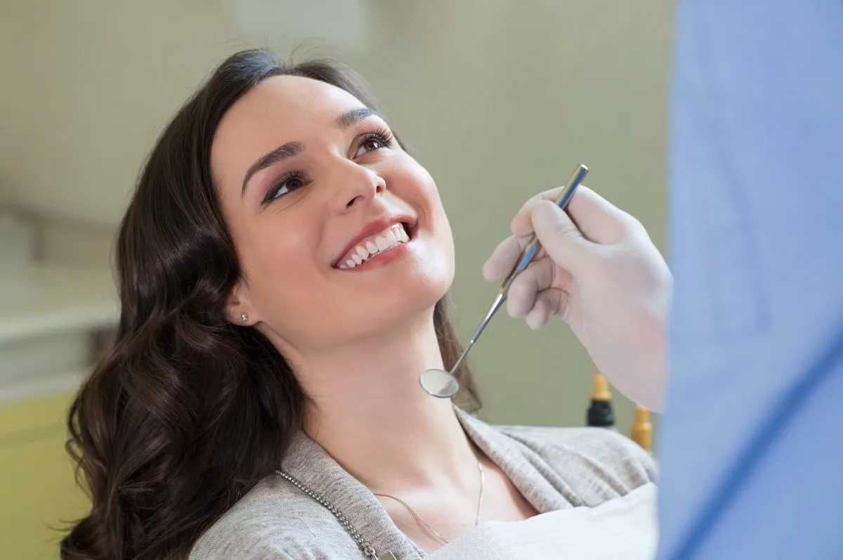 Happy couple smiling outdoors - Sunrise Dental Arts Care Closeup of dentist examining young woman's teeth