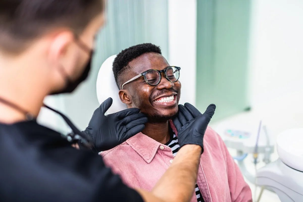 Happy couple smiling outdoors - Sunrise Dental Arts Care African American young man having a visit at the dentist's. He is sitting on chair at dentist office in dental clinic.