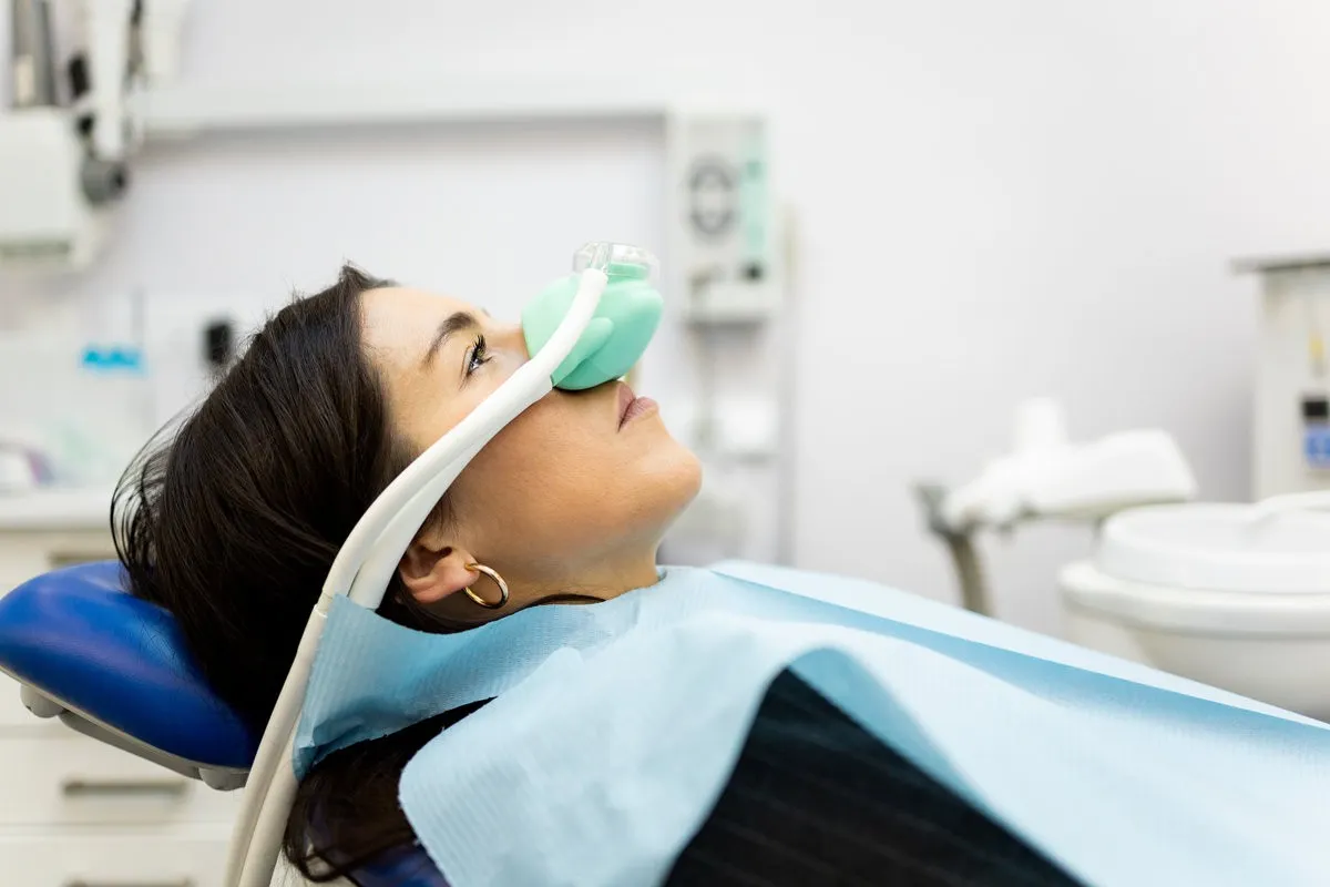 Happy couple smiling outdoors - Sunrise Dental Arts Care An adult woman sits in a dentist's office wearing a nasal mask to inhale nitrous oxide. Dentist fear concept. Feeling of relaxation with laughing gas.