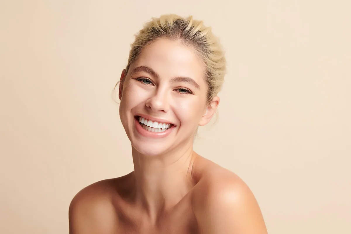 Man pointing at bright smile - Sunrise Dental Arts Care Beautiful smile young woman. White teeth on white background,