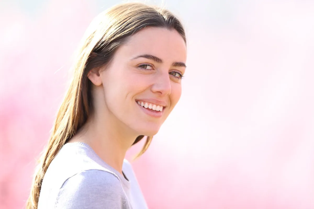 Happy couple smiling outdoors - Sunrise Dental Arts Care Beautiful woman looking at camera in a pink field