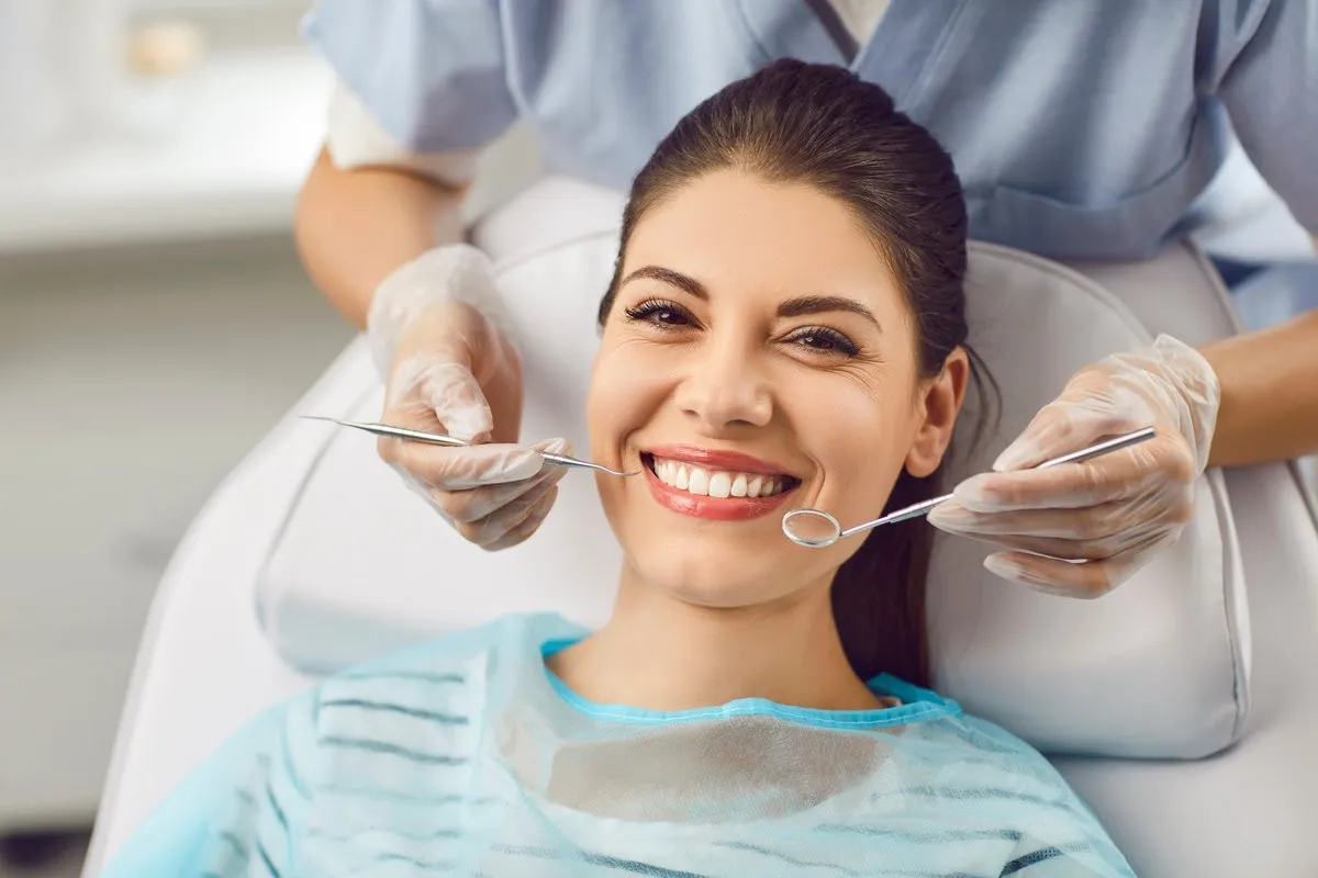 Happy couple smiling outdoors - Sunrise Dental Arts Care Portrait of a smiling patient with dentist doctor is checking teeth with a dental instrument. Dental care provided during the medical visit, regular dentistry check up for maintaining oral health.