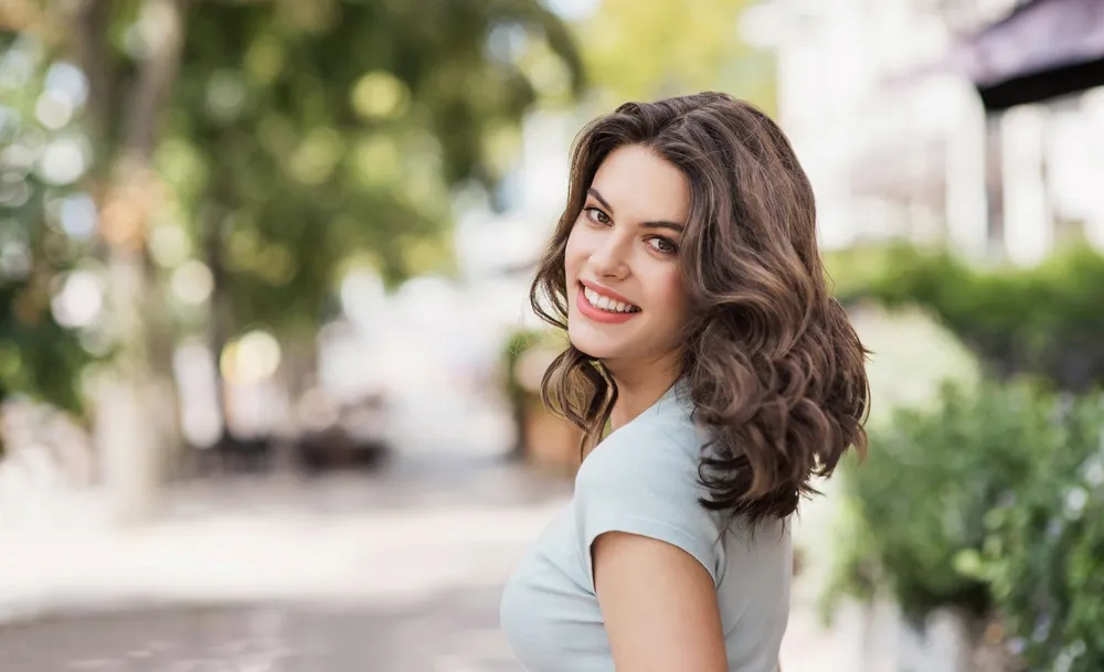Woman with a bright white smile walking confidently on a city street