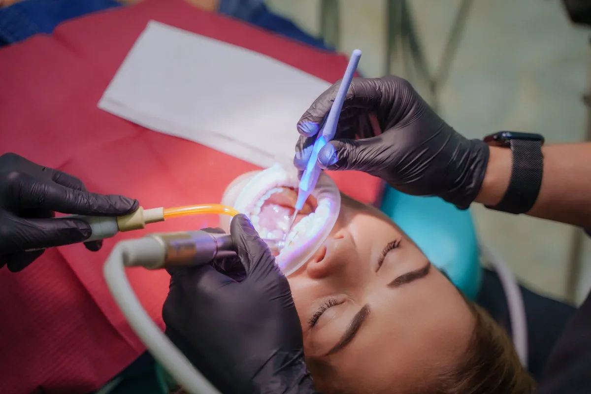Couple smiling while looking at phone - Sunrise Dental Arts Care The dentist administers anesthesia to the patient. Dental treatment in a private medical clinic. The patient is injected with the drug from a syringe into the gum