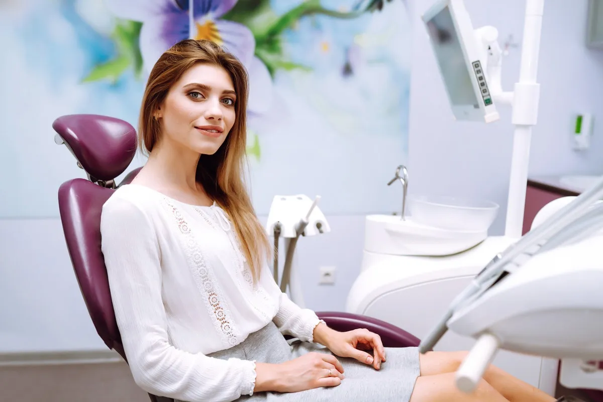 Couple smiling while looking at phone - Sunrise Dental Arts Care Young woman at the dentist's chair during a dental procedure. Overview of dental caries prevention. Healthy Smile.