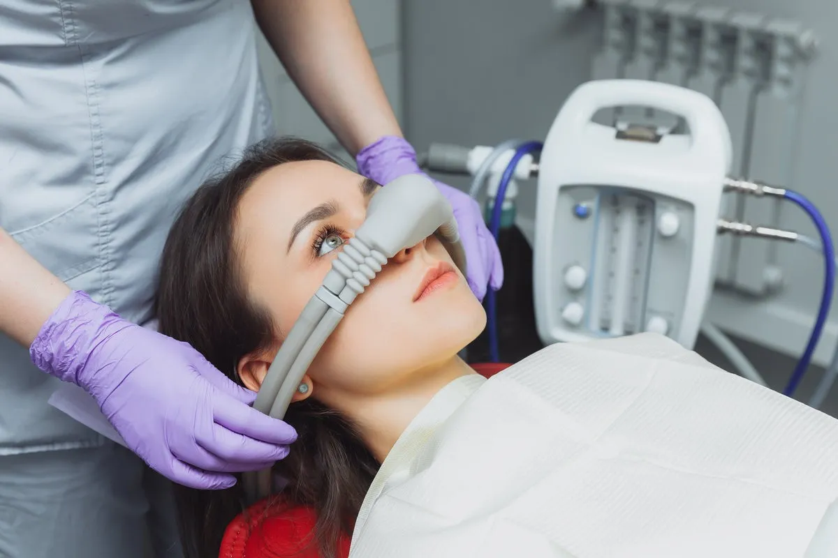 Couple smiling while looking at phone - Sunrise Dental Arts Care dentist puts inhalation sedative mask on his patient