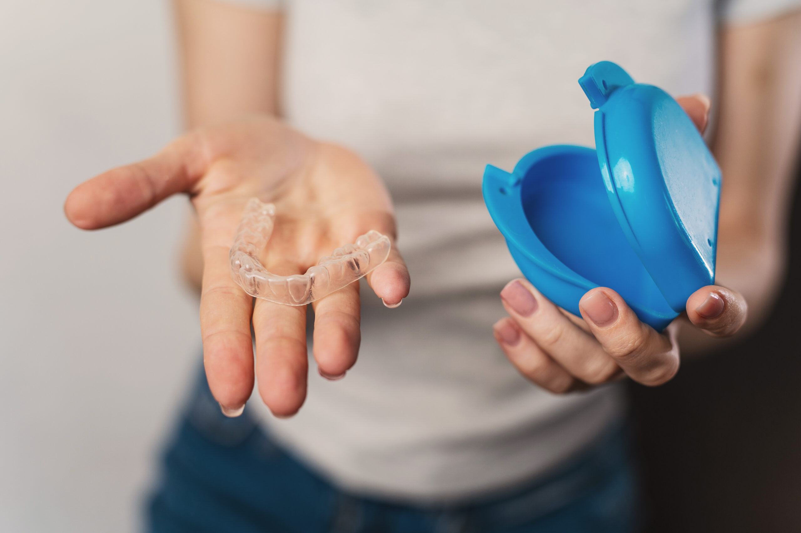 Woman holding a clear custom nightguard used to protect teeth from bruxism