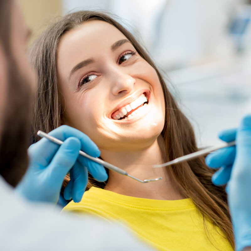 Dental hygienist performing a professional teeth cleaning on a patient at Sunrise Dental Arts